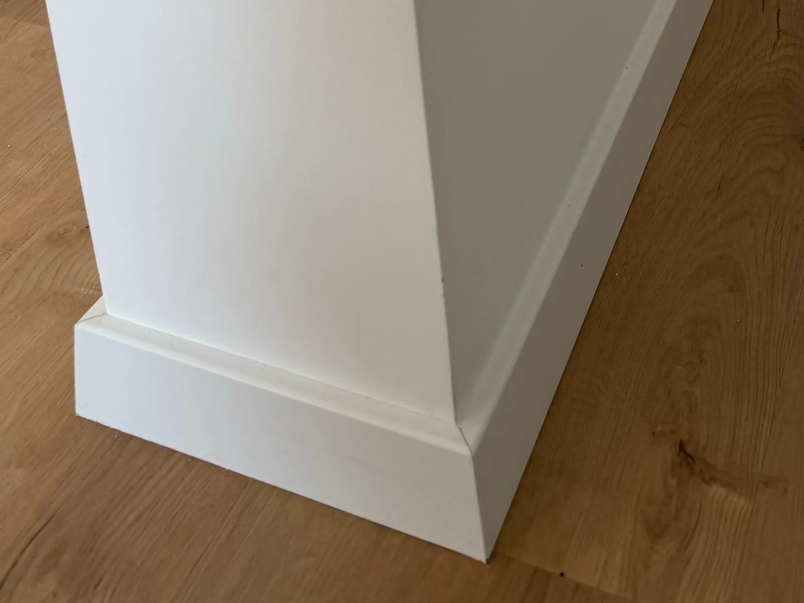 Sauber gesetzte Sockelleiste an einer Wandecke, mit Vinylboden — Lomi-Bau